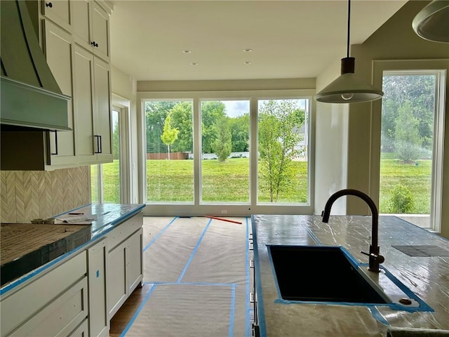 10303 W 151st Ter, Overland Park, KS 66221 - kitchen featuring decorative backsplash, wall chimney exhaust hood, white cabinets, and decorative light fixtures