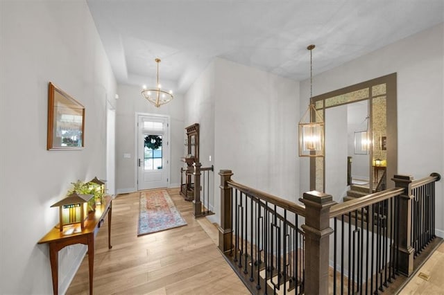 foyer entrance featuring a chandelier, wood finished floors, and baseboards