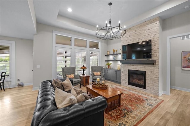 living area featuring light wood-type flooring, a chandelier, a tray ceiling, baseboards, and recessed lighting