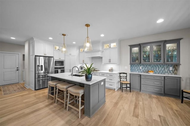 kitchen featuring stainless steel appliances, premium range hood, a sink, light countertops, and backsplash
