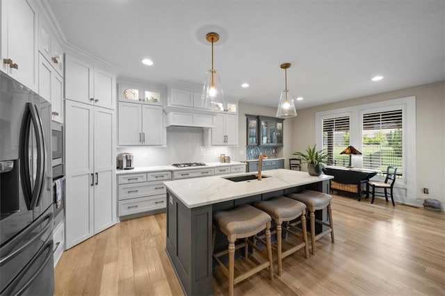 kitchen with stainless steel refrigerator with ice dispenser, a sink, white cabinets, recessed lighting, and a breakfast bar