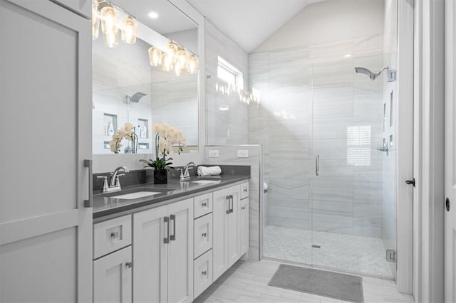 bathroom with double vanity, a shower stall, and vaulted ceiling