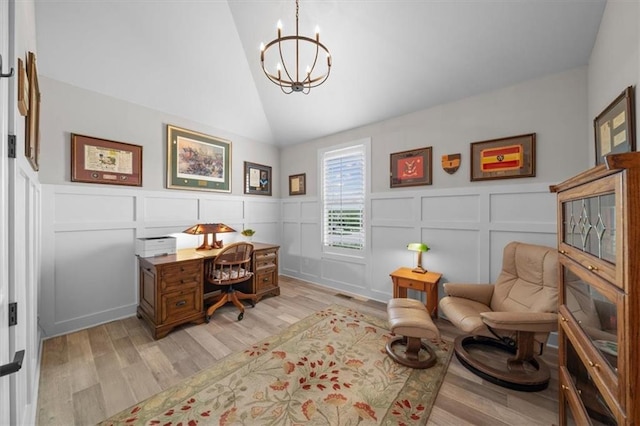 office area featuring vaulted ceiling, a decorative wall, a chandelier, light wood-type flooring, and wainscoting