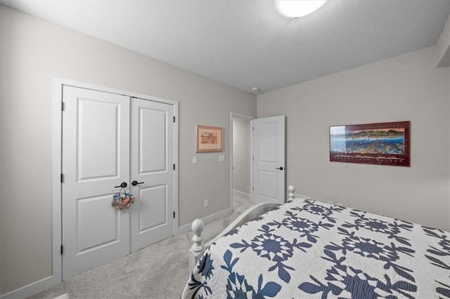 carpeted bedroom featuring baseboards, a textured ceiling, and a closet
