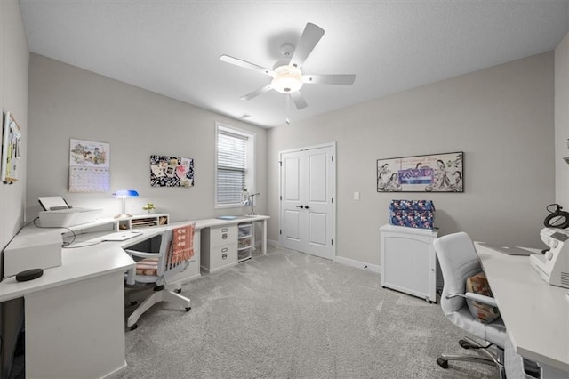 office with a ceiling fan, light colored carpet, baseboards, and a textured ceiling