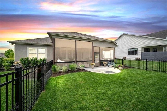 back of property at dusk featuring a patio, a sunroom, and stucco siding