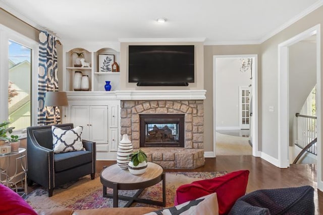 living room with crown molding, a stone fireplace, plenty of natural light, and wood finished floors