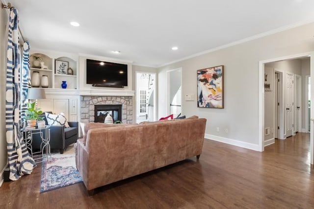 living area featuring baseboards, ornamental molding, wood finished floors, and a fireplace