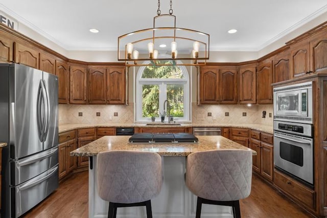 kitchen with dark wood-style flooring, a kitchen breakfast bar, light stone counters, a sink, and appliances with stainless steel finishes