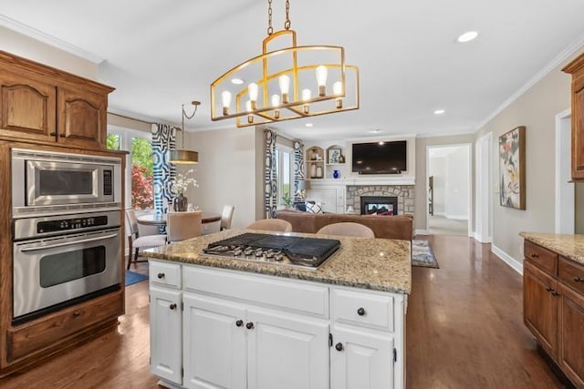 kitchen with dark wood-style flooring, appliances with stainless steel finishes, recessed lighting, a kitchen island, and ornamental molding