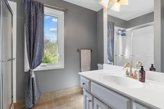 full bathroom featuring vanity, baseboards, plenty of natural light, and a stall shower