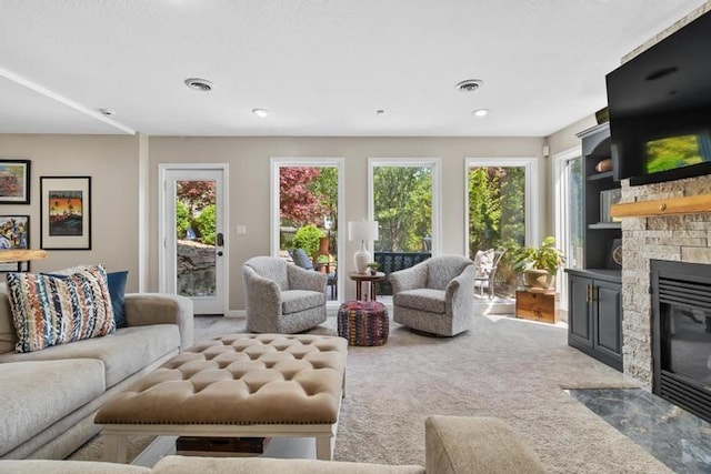 living area featuring visible vents, a fireplace with flush hearth, and carpet