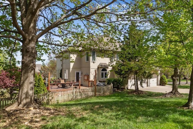 rear view of house with fence, concrete driveway, a lawn, and a garage
