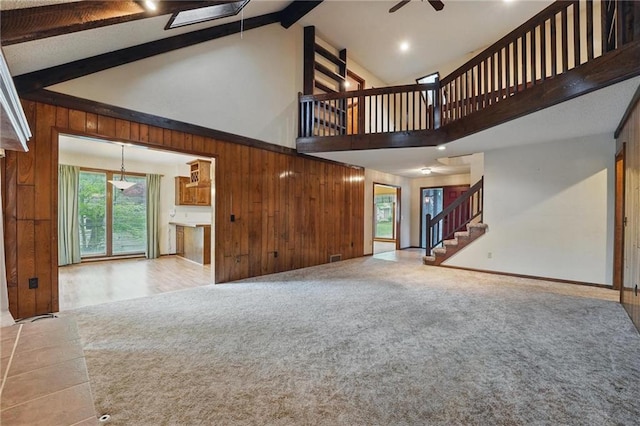 10503 W 50th Ter, Shawnee, KS 66203 - unfurnished living room featuring high vaulted ceiling, beam ceiling, stairway, wood walls, and a ceiling fan