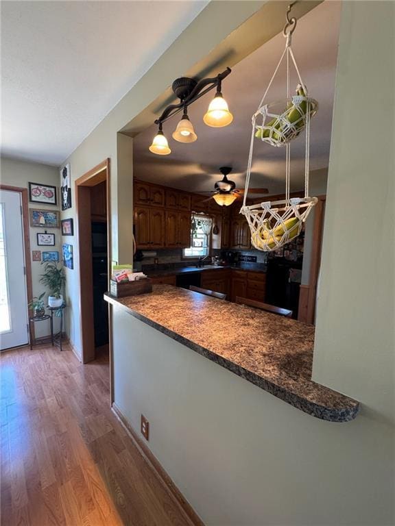 166 Crescent Dr, Chillicothe, MO 64601 - kitchen with dark countertops, a ceiling fan, wood finished floors, and a peninsula