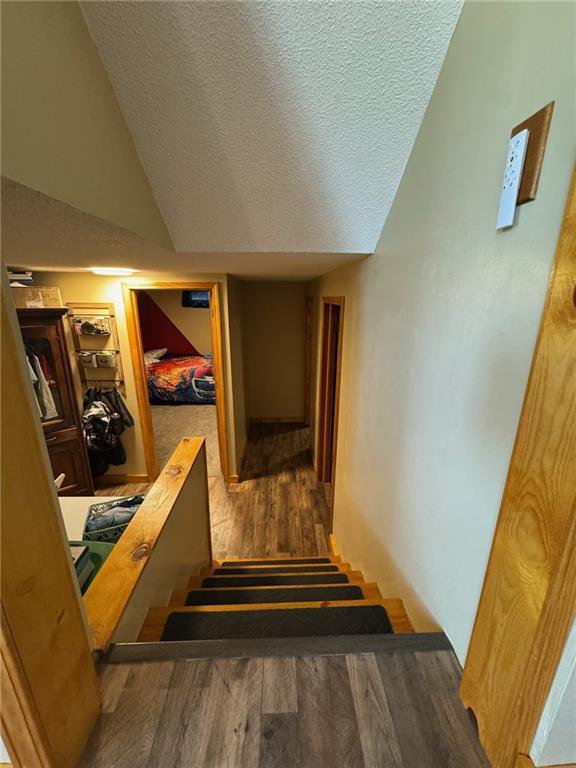 166 Crescent Dr, Chillicothe, MO 64601 - corridor featuring wood finished floors, a textured ceiling, lofted ceiling, and stairway