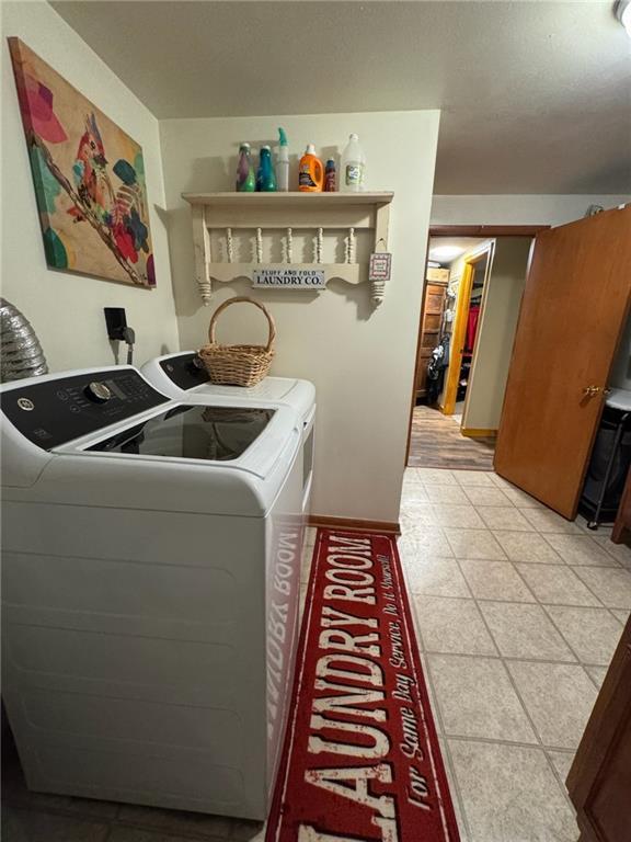 166 Crescent Dr, Chillicothe, MO 64601 - clothes washing area with washing machine and dryer, baseboards, and light tile patterned floors