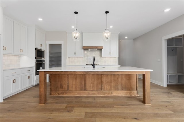 kitchen featuring stainless steel microwave, backsplash, white cabinetry, and light countertops