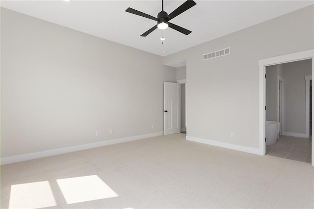unfurnished bedroom with baseboards, visible vents, light colored carpet, ceiling fan, and ensuite bath