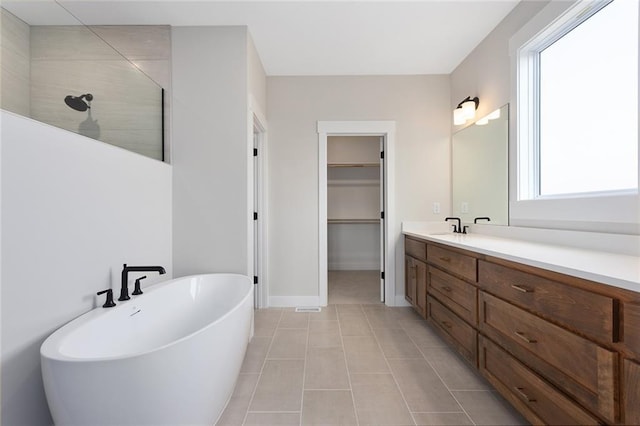 full bath with a soaking tub, a walk in shower, tile patterned flooring, vanity, and a walk in closet