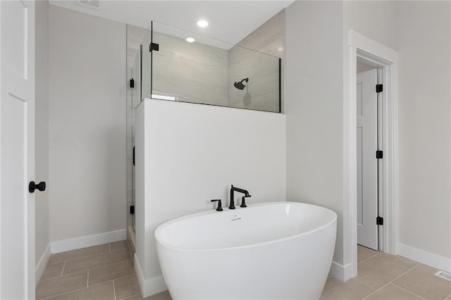 full bathroom with a freestanding bath, baseboards, tile patterned flooring, and a stall shower