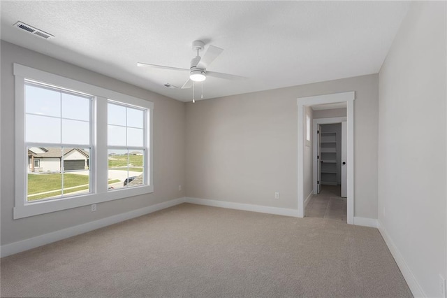 unfurnished room with light carpet, baseboards, visible vents, and a ceiling fan