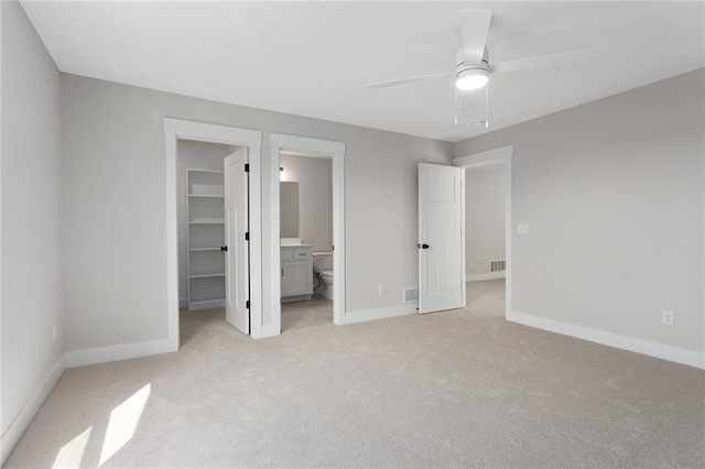 unfurnished bedroom with a spacious closet, baseboards, light colored carpet, and a closet