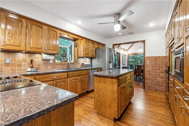 4710 Monrovia St, Shawnee, KS 66216 - kitchen with appliances with stainless steel finishes, brown cabinetry, a center island, a ceiling fan, and light wood-style flooring