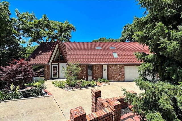 4710 Monrovia St, Shawnee, KS 66216 - tudor house with a tile roof, concrete driveway, brick siding, and a garage
