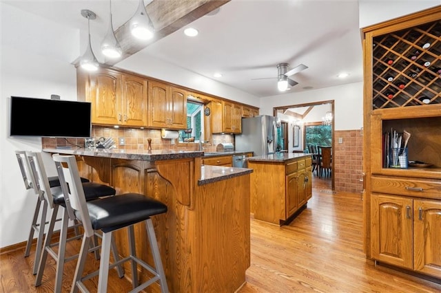 4710 Monrovia St, Shawnee, KS 66216 - kitchen featuring stainless steel appliances, a kitchen island, a peninsula, light wood-style flooring, and healthy amount of natural light