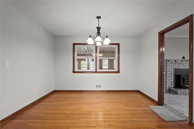 8416 Westridge Rd, Raytown, MO 64138 - unfurnished dining area with baseboards, a wood stove, a notable chandelier, and light wood-style flooring