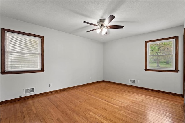 8416 Westridge Rd, Raytown, MO 64138 - unfurnished room with visible vents, ceiling fan, baseboards, light wood-type flooring, and a textured ceiling