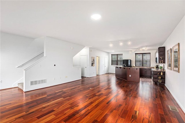 4581 Madison Ave, Kansas City, MO 64111 - living room featuring dark wood-style floors, stairway, rail lighting, and baseboards