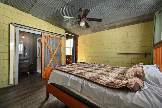 4353 NW State Route Ff, Adrian, MO 64720 - bedroom featuring a barn door, dark wood-style flooring, a ceiling fan, and concrete block wall