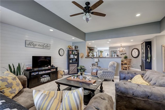 living area featuring recessed lighting, light colored carpet, and ceiling fan with notable chandelier