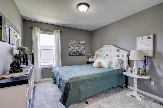 bedroom with baseboards, a textured ceiling, visible vents, and light carpet
