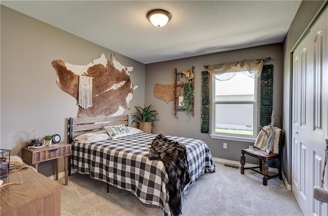 bedroom featuring a textured ceiling, baseboards, light carpet, and a closet
