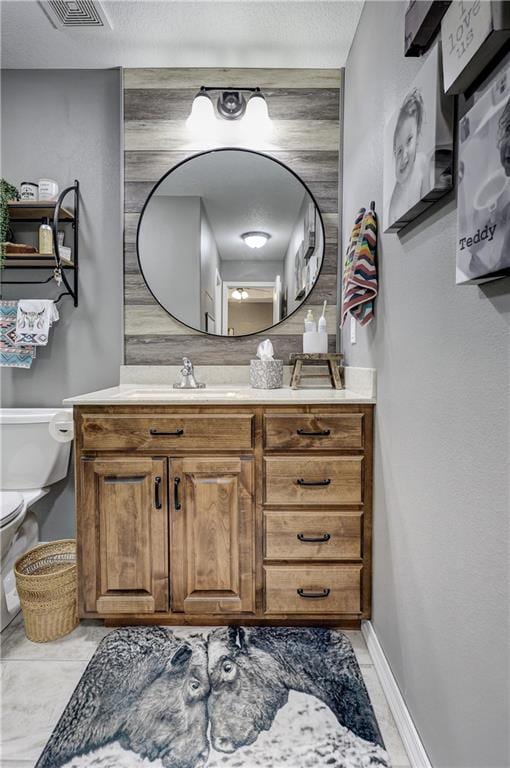 bathroom featuring vanity, toilet, a textured ceiling, baseboards, and visible vents