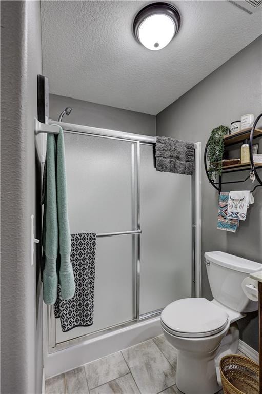full bath with toilet, a textured ceiling, and a stall shower