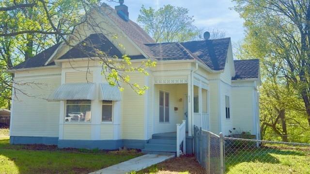 628 S Clay St, Nevada, MO 64772 - view of front of property featuring fence, a chimney, and a shingled roof