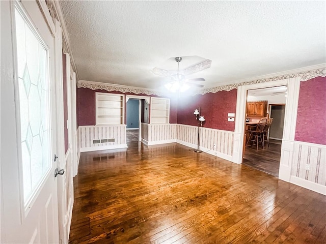 628 S Clay St, Nevada, MO 64772 - empty room featuring crown molding, hardwood / wood-style floors, a textured ceiling, a wainscoted wall, and a ceiling fan