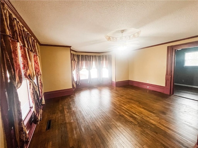 628 S Clay St, Nevada, MO 64772 - empty room featuring visible vents, ornamental molding, a textured ceiling, hardwood / wood-style flooring, and a ceiling fan