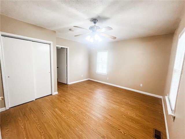 628 S Clay St, Nevada, MO 64772 - unfurnished bedroom with a ceiling fan, baseboards, light wood-type flooring, visible vents, and a closet