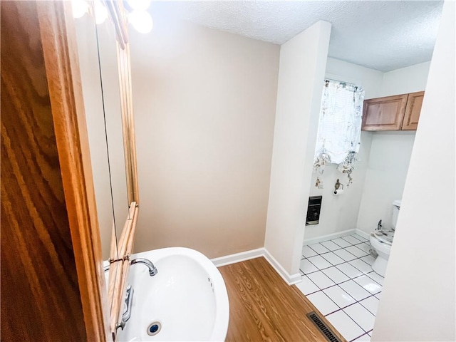 628 S Clay St, Nevada, MO 64772 - bathroom featuring visible vents, toilet, baseboards, a textured ceiling, and a sink