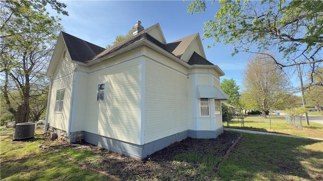 628 S Clay St, Nevada, MO 64772 - view of property exterior featuring a lawn, fence, cooling unit, and a chimney