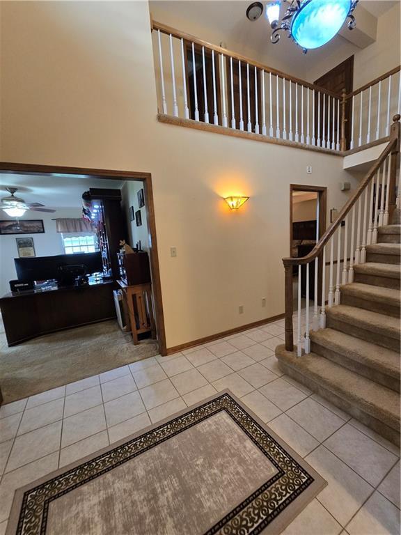 1502 Hillcrest Ct, Atchison, KS 66002 - entryway featuring light tile patterned floors, a ceiling fan, stairway, a towering ceiling, and baseboards