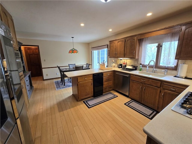 1502 Hillcrest Ct, Atchison, KS 66002 - kitchen with stainless steel appliances, a peninsula, a sink, light countertops, and hanging light fixtures