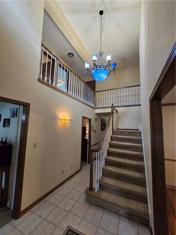 1502 Hillcrest Ct, Atchison, KS 66002 - staircase featuring tile patterned floors, a chandelier, a high ceiling, and baseboards