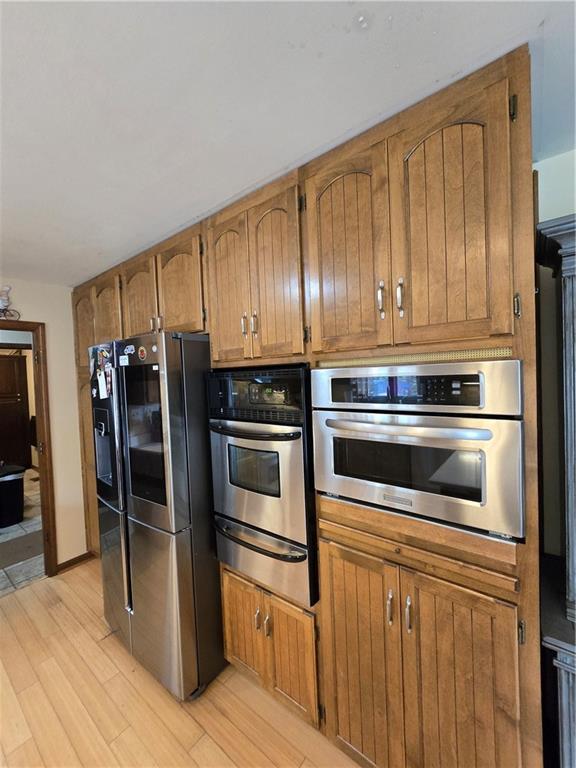 1502 Hillcrest Ct, Atchison, KS 66002 - kitchen with stainless steel appliances, a warming drawer, brown cabinetry, and light wood finished floors