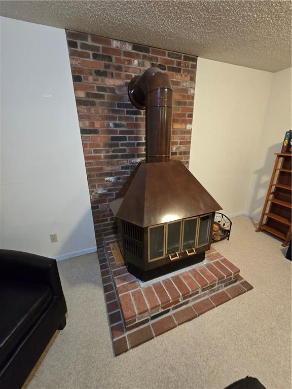1502 Hillcrest Ct, Atchison, KS 66002 - detailed view of a wood stove, carpet floors, baseboards, and a textured ceiling